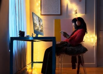 24-Zoll-iMac in Blau auf einem Schreibtisch in abgedunkeltem Raum, dessen Displaytechnik beim OLED iMac auf fünf Leuchtschichten umgestellt werden könnte