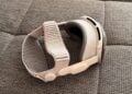 Apple Vision Pro mit hellem Dual Knit Band liegt seitlich auf einer grau melierten Sofafläche