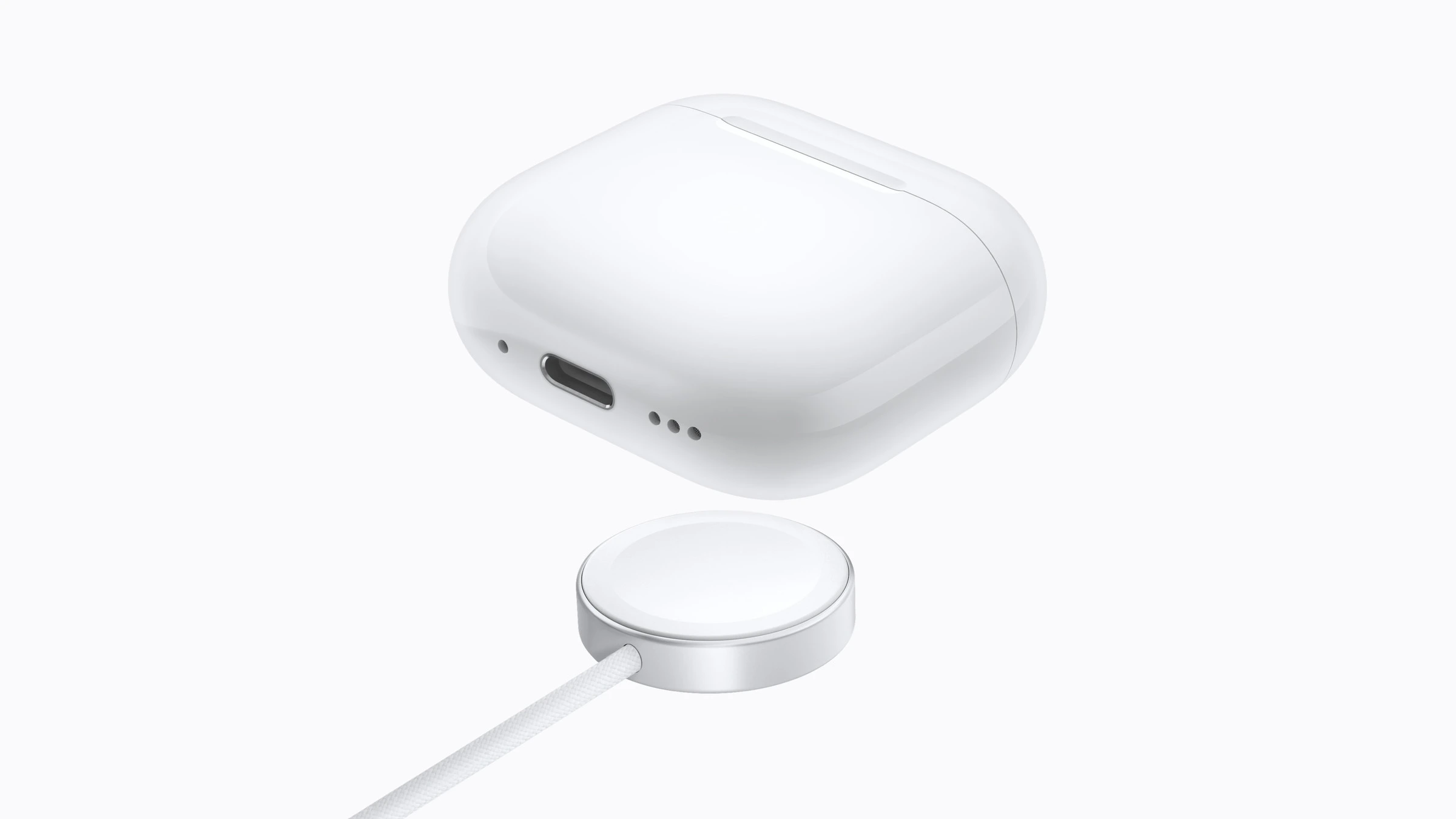Ladecase der AirPods 5 über einem Apple Watch Ladegerät, daneben der USB-C Anschluss am Case