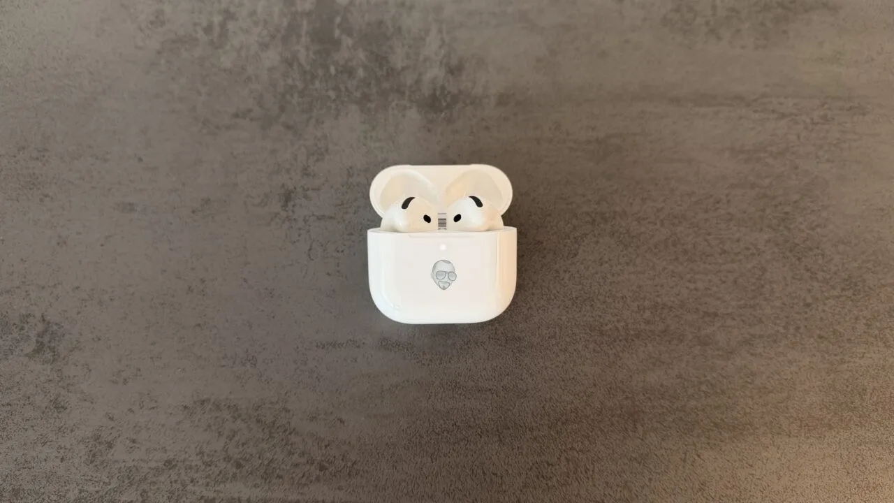 AirPods 5 im geöffneten Ladecase mit Memoji-Gravur auf grauem Steinuntergrund