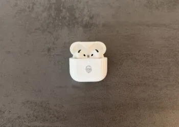 AirPods 5 im geöffneten Ladecase mit Memoji-Gravur auf grauem Steinuntergrund