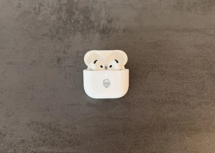 AirPods 5 im geöffneten Ladecase mit Memoji-Gravur auf grauem Steinuntergrund