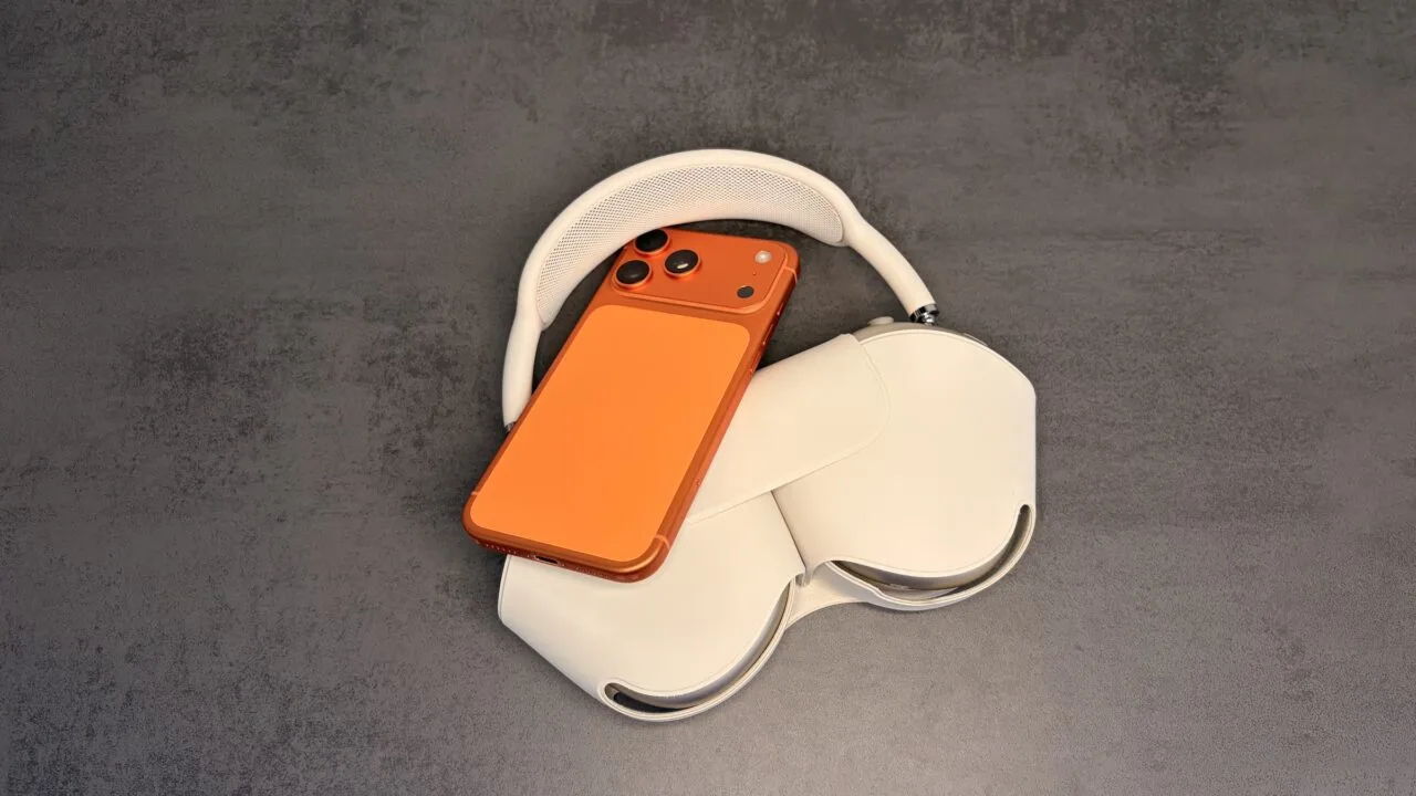 AirPods-Equalizer einstellen: orangefarbenes iPhone auf AirPods Max in der Hülle auf grauem Untergrund