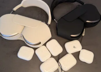 Mehrere AirPods Ladecases und zwei AirPods Max auf einem grauen Untergrund, Sinnbild für die AirPods Firmware aller Modelle