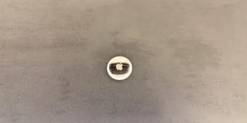 Apple KI-Pin: ein AirTag als Größenvergleich auf grauer Fläche