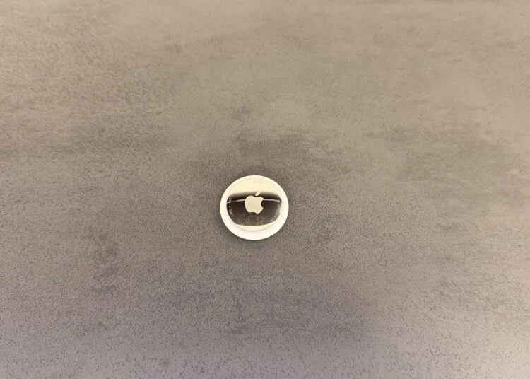 Apple KI-Pin: ein AirTag als Größenvergleich auf grauer Fläche