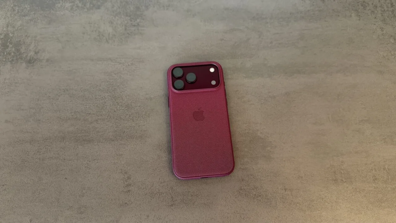 Rückseite eines iPhone 18 Pro Max in weinroter Hülle auf grauem Untergrund, betroffen von der verlängerten Apple Qualcomm Patentlizenz