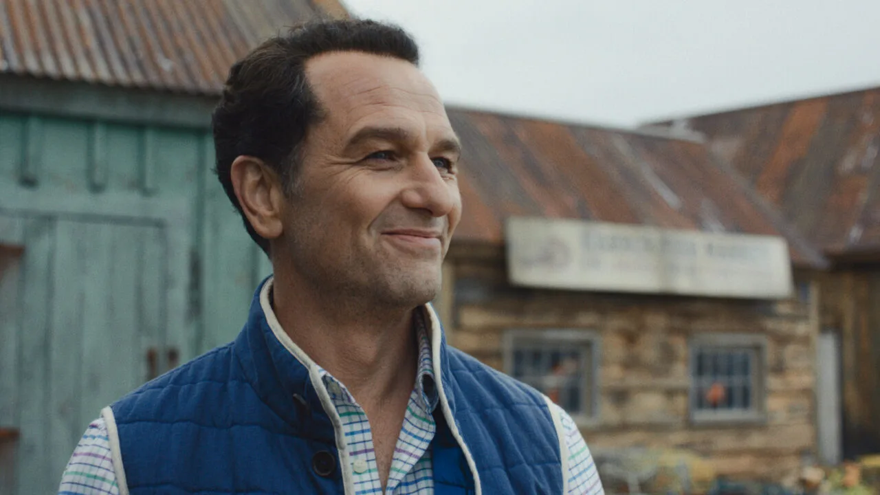 Apple TV Emmys: Matthew Rhys als Bürgermeister in der Serie Widow's Bay vor Holzhäusern des Inselorts