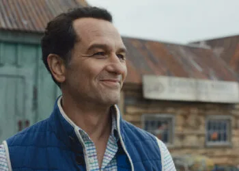 Apple TV Emmys: Matthew Rhys als Bürgermeister in der Serie Widow's Bay vor Holzhäusern des Inselorts
