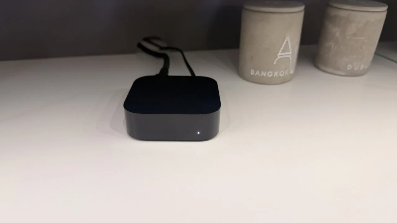 Apple TV 4K A19: schwarze Apple-TV-Box mit leuchtender Statusanzeige auf einer hellen Ablage