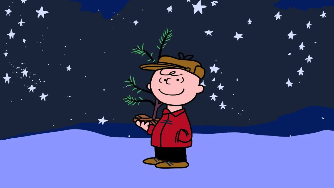 Charlie Brown mit kleinem Weihnachtsbaum unter Sternenhimmel im Schnee, Szene aus A Charlie Brown Christmas, das bei Apple TV wieder gratis läuft