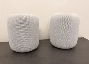 HomePod Surround: zwei weiße HomePod-Lautsprecher nebeneinander auf einer dunklen Arbeitsplatte