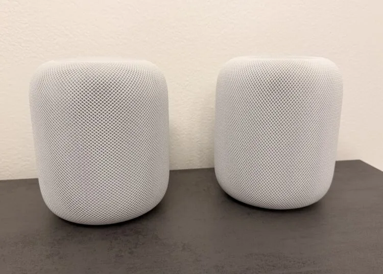 HomePod Surround: zwei weiße HomePod-Lautsprecher nebeneinander auf einer dunklen Arbeitsplatte