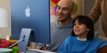 Ein Kind sitzt mit einem Erwachsenen vor einem blauen iMac, Motiv zu Apples Leitfaden für Bildschirmzeit in Familien
