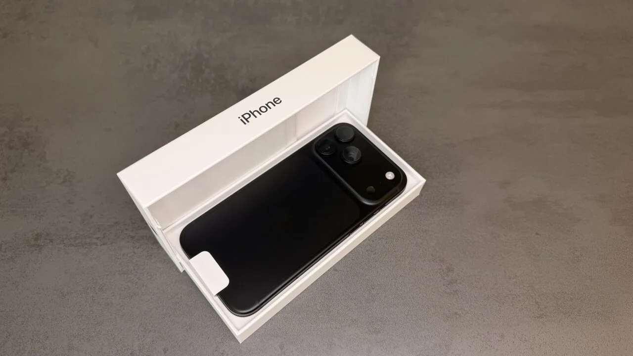iPhone 18 Pro Max in Schwarz mit der Rückseite nach oben in der geöffneten Originalverpackung auf grauem Steinuntergrund