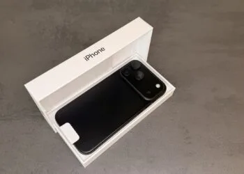 iPhone 18 Pro Max in Schwarz mit der Rückseite nach oben in der geöffneten Originalverpackung auf grauem Steinuntergrund