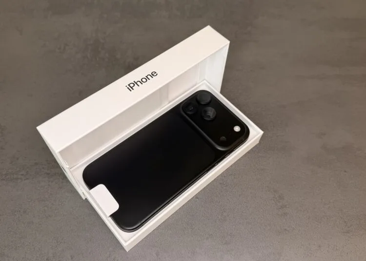 iPhone 18 Pro Max in Schwarz mit der Rückseite nach oben in der geöffneten Originalverpackung auf grauem Steinuntergrund