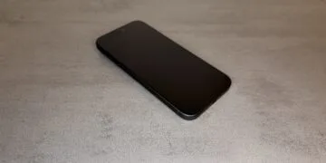 iPhone 20 Display im Vergleich: aktuelles schwarzes iPhone Pro mit flachem Display schräg von oben auf grauer Steinoberfläche