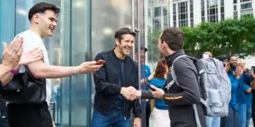 John Ternus begrüßt vor dem Apple Store Fifth Avenue in New York einen Kunden per Handschlag, umringt von applaudierenden Mitarbeitern
