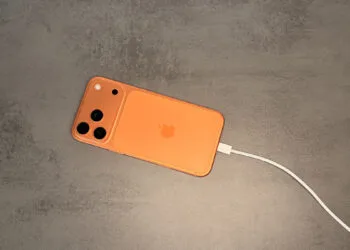 iPhone in oranger Hülle am USB-C-Kabel, Ausgangspunkt für Juice Jacking an fremden Anschlüssen