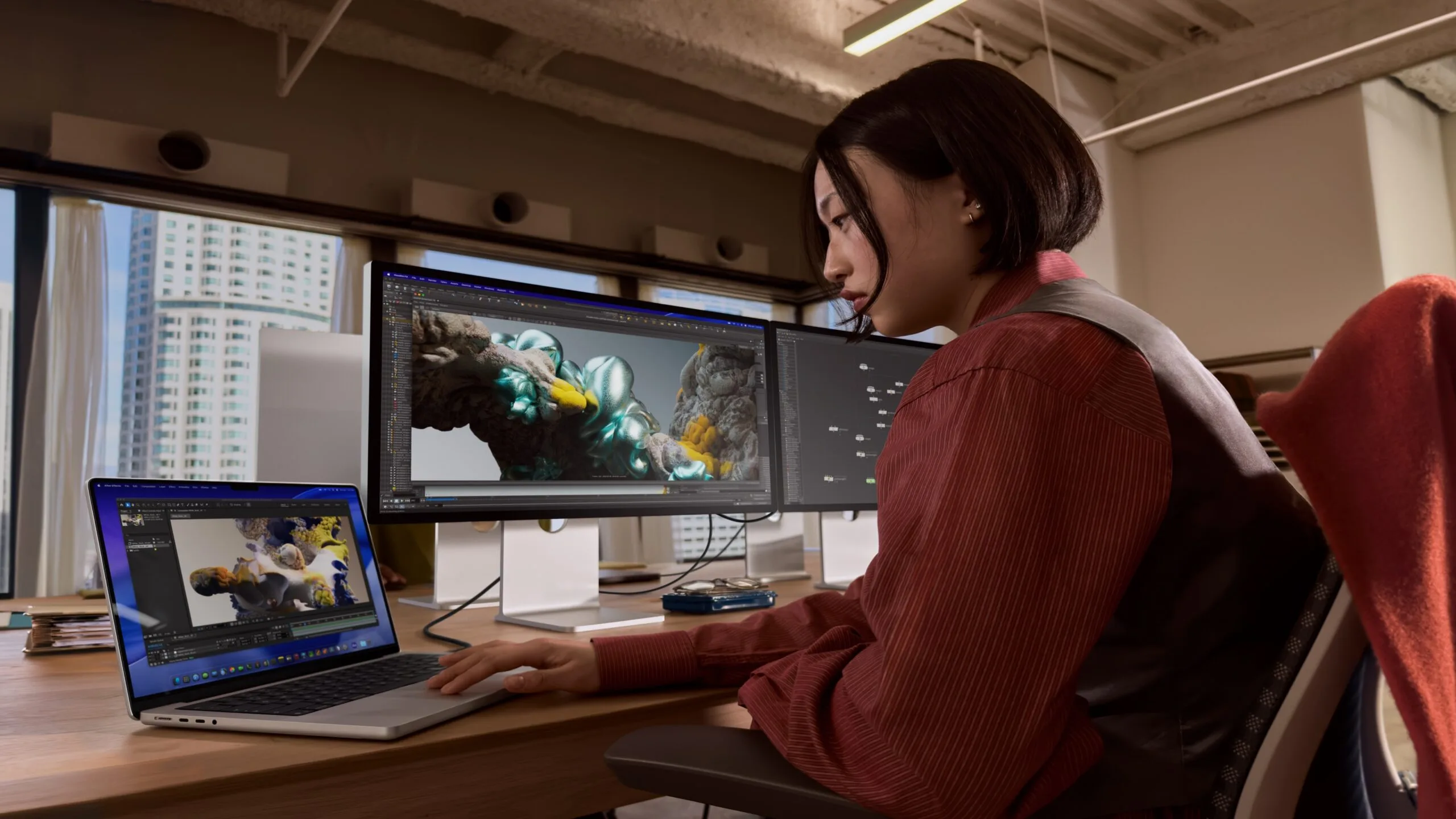 Mac Kaufberatung: Frau arbeitet an einem MacBook Pro in Silber, daneben zwei externe Displays mit 3D-Software