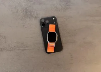 Taptic Engine in iPhone und Apple Watch: schwarzes iPhone mit Dreifachkamera, darauf eine Apple Watch Ultra mit orangefarbenem Alpine Loop