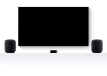 tvOS 27.2 HomePod Surround: zwei HomePods links und rechts eines Fernsehers, dazwischen ein Apple TV 4K auf einem weißen Sideboard