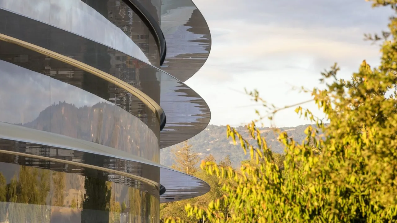 Die geschwungene Glasfassade des Apple Park in Cupertino mit Bäumen davor – Sitz von Apple, das sich im DOJ-Kartellverfahren verteidigt