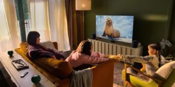Apple Event Welcome home: Familie im Wohnzimmer vor einem Fernseher mit Apple TV, daneben zwei HomePod und hinter dem Sofa zwei grüne HomePod mini