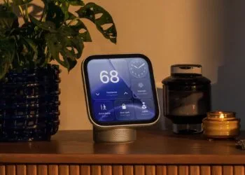 Apple HomeView Reparatur: HomeView auf einer Holzkommode, auf dem Display Thermostat, Uhr, Gegensprechanlage und Steuerung für Türschloss und Licht, daneben eine Pflanze und eine Kerze