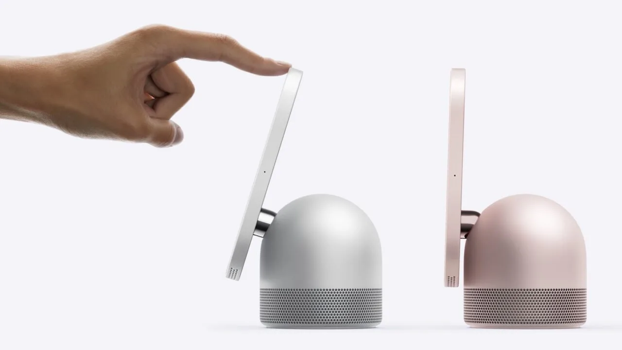 HomeView Roboterarm: Eine Hand neigt mit einem Finger das Display einer silbernen HomeView, daneben steht ein zweites Modell in Rosa