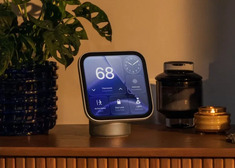 Apple HomeView Siri AI: die Smart-Home-Zentrale auf einem Holz-Sideboard, auf dem Display Thermostat, Uhr, Türschloss und Licht, daneben eine Pflanze und eine Kerze