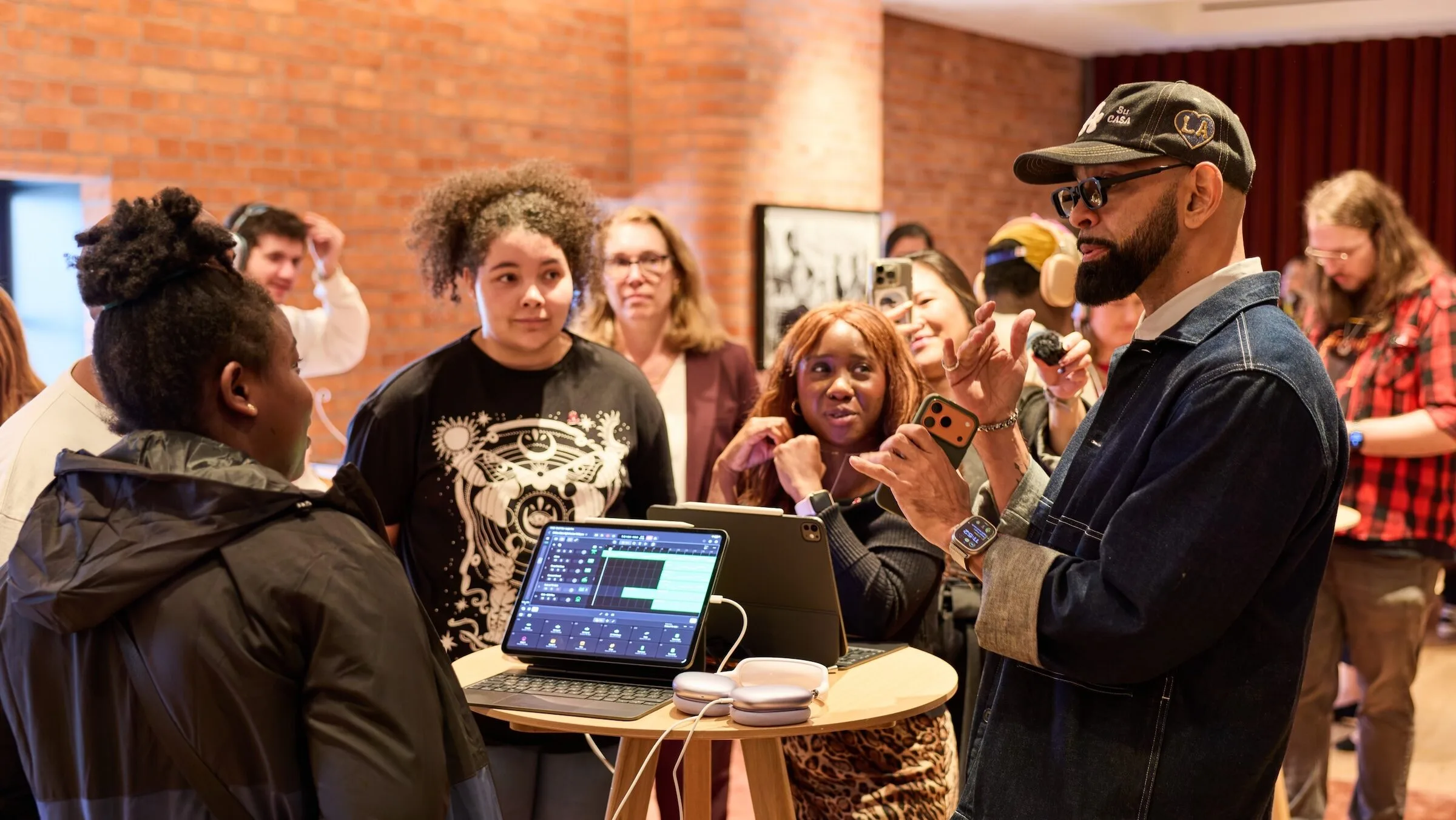 Apple King's Trust: Workshopleiter erklärt Teilnehmenden der Creative Labs die Musikproduktion am iPad, daneben AirPods Max