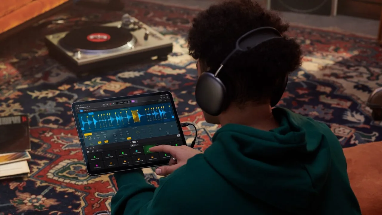 Apple Samplab: Person mit Kopfhörern bearbeitet in Logic Pro auf dem iPad eine in Abschnitte zerlegte Audiospur, im Hintergrund ein Plattenspieler