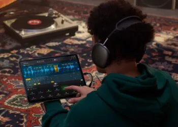 Apple Samplab: Person mit Kopfhörern bearbeitet in Logic Pro auf dem iPad eine in Abschnitte zerlegte Audiospur, im Hintergrund ein Plattenspieler