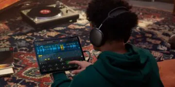 Apple Samplab: Person mit Kopfhörern bearbeitet in Logic Pro auf dem iPad eine in Abschnitte zerlegte Audiospur, im Hintergrund ein Plattenspieler