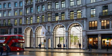 Apple Store Regent Street in London in der Abenddämmerung mit vier Glasbögen, weißer Apple-Fahne und rotem Doppeldeckerbus, Symbol für die Apple Stores, die Kartons mit Sperrfrist erhalten haben