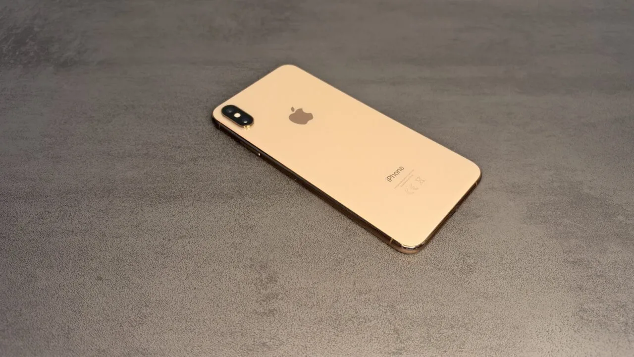 Goldenes iPhone mit Doppelkamera auf grauer Fläche – iPhones ohne aktuelle Updates sind das Ziel von DarkSword