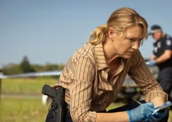 Szenenbild aus Dustfall bei Apple TV: Anna Torv als Ermittlerin Tig Pollard kniet mit Notizblock und Handschuhen an einem abgesperrten Tatort, im Hintergrund ein Polizist