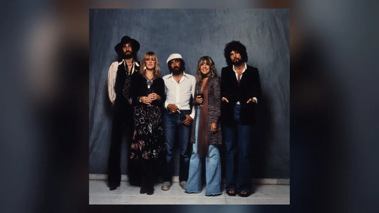 Die fünf Mitglieder von Fleetwood Mac stehen nebeneinander vor einem blauen Tuch, Bandfoto zur Fleetwood Mac Doku bei Apple TV
