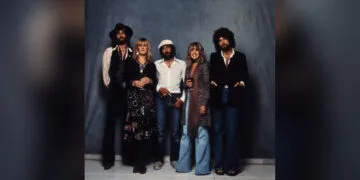 Die fünf Mitglieder von Fleetwood Mac stehen nebeneinander vor einem blauen Tuch, Bandfoto zur Fleetwood Mac Doku bei Apple TV