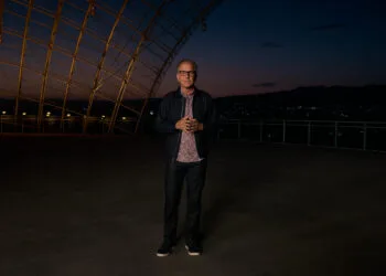 Greg Joswiak, Apples Marketingchef, steht in der Abenddämmerung auf einer Terrasse unter einer geschwungenen Stahl-Glas-Konstruktion