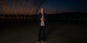 Greg Joswiak, Apples Marketingchef, steht in der Abenddämmerung auf einer Terrasse unter einer geschwungenen Stahl-Glas-Konstruktion