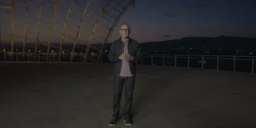 Greg Joswiak, Apples Marketingchef, steht in der Abenddämmerung auf einer Terrasse unter einer geschwungenen Stahl-Glas-Konstruktion