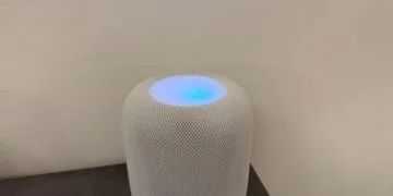 Weißer HomePod mit leuchtender Oberseite in Blau- und Violetttönen vor einer hellen Wand – so sieht HomePod Sound-Leuchten aus