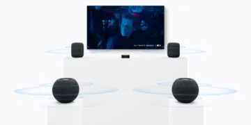 HomePod Surround Einstellungen: zwei große HomePods neben einem Fernseher, davor zwei HomePod mini auf Sockeln und ein Apple TV in der Mitte