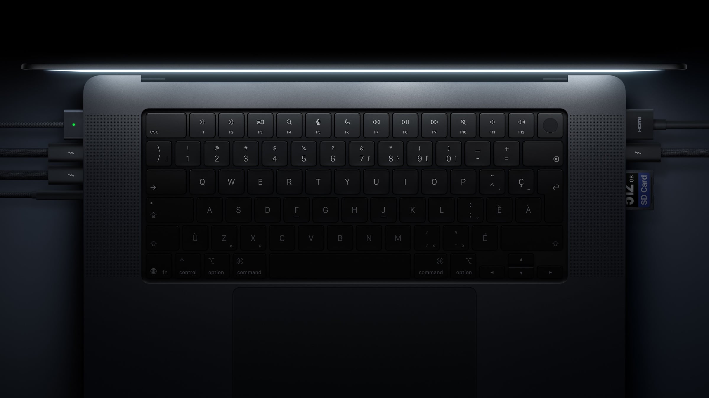 iPad Pro vs. MacBook Pro: top view of the space black MacBook Pro with PROLED XDR display keyboard, with MagSafe, Thunderbolt and HDMI cables and an SD card plugged in at the sides
