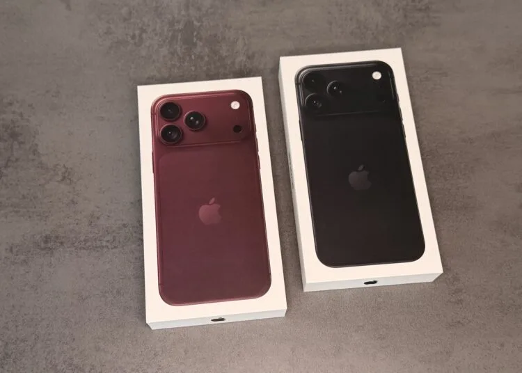 Zwei Verpackungen des iPhone 18 Pro in Burgunder und Schwarz auf einer grauen Fläche