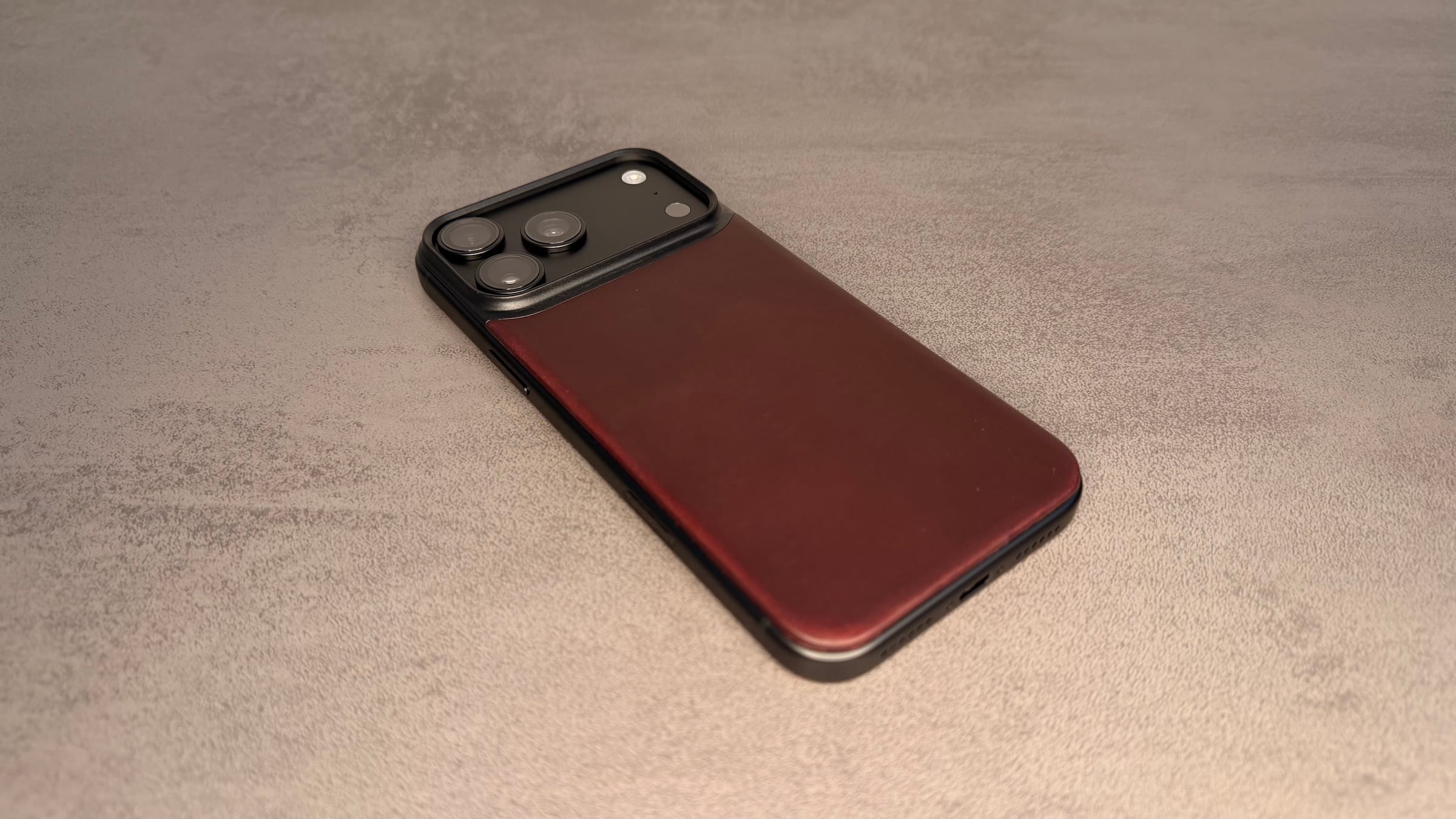Nomad cases iPhone 18 Pro: Mag Leather Back in Burgundy on the back of a black iPhone, on a grey surface