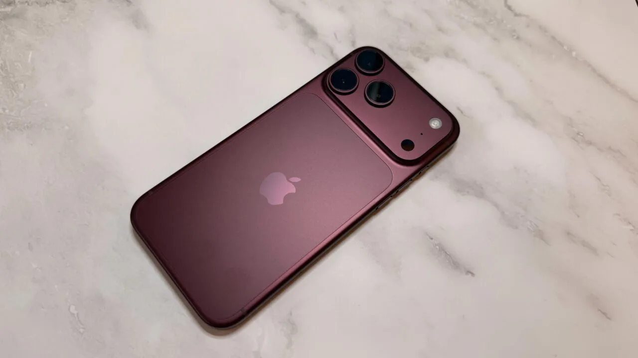 iPhone China Marktanteil: dunkelrotes iPhone aus der Pro-Reihe von hinten auf einer hellen Marmorfläche, mit Kameraplateau und drei Objektiven